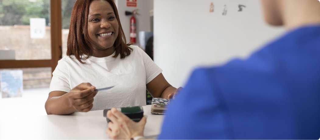 Dental patient giving her card to dental staff to process payment 