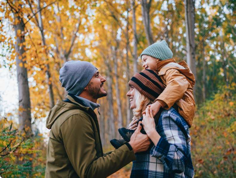 Happy family enjoying an autumn walk in the woods, sharing smiles and laughter—capturing the joy of a healthy lifestyle supported by excellent dental care.