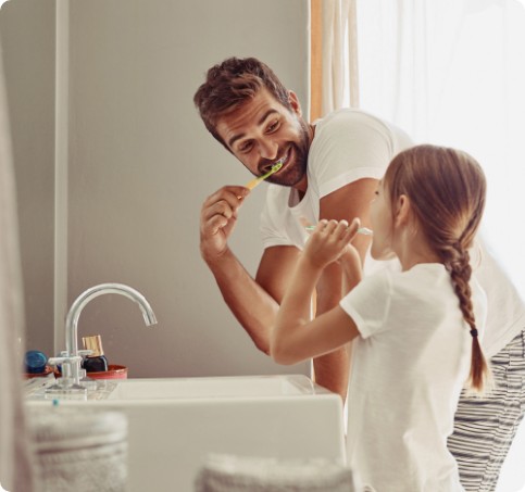 A father teaching her daughter how to properly brush teeth