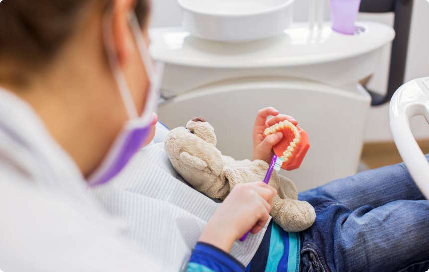 A dentist teaching a pediatric patient the proper way of brushing